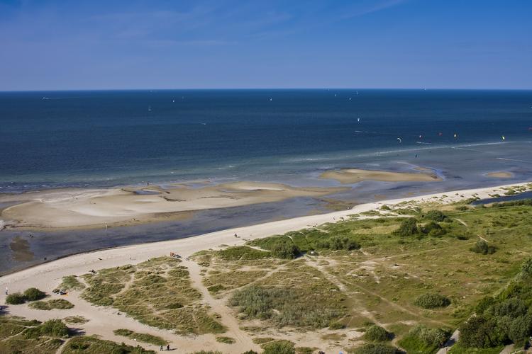 Das Bild zeigt die Kieler Förde mit einem sandigen Strand, Dünenlandschaft im Vordergrund und dem offenen Meer im Hintergrund
